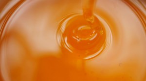Honey pouring in container closeup