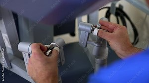 Surgeon moving master manipulators sitting at control unit. Doctor carrying out the operation of minimal invasion using advanced technology equipment. Close up.