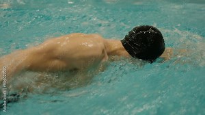 A powerful image of a swimmer fully immersed in the clear, turquoise waters of a swimming pool, capturing the intensity and motion of competitive swimming. Immersed in a Pool with Turquoise Water