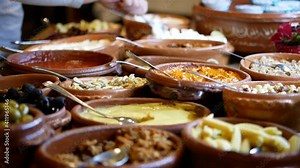 Appetizer on the self-service table in the hotel, canned salads in ceramic bowls, olives, chickpeas, artichokes, almonds in oil, ketchup, small corn cobs
