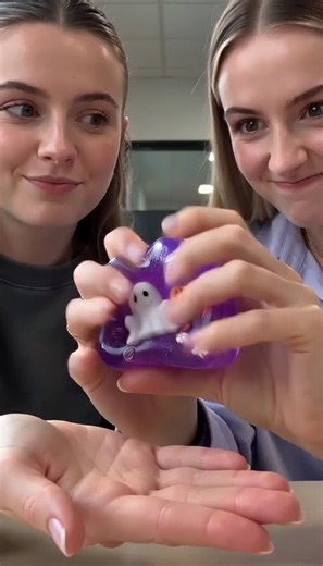 Two colleagues take turns with a slow-rising Halloween ghost squeeze cube.