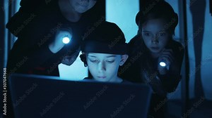 Talented boy hacker coding at laptop monitor hacking a modern database server room. Spy kids working on program code activating data center secure storage.