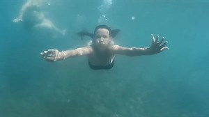Underwater shooting: A young woman dives and swims and dances underwater