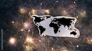 world map surrounded by fairy lights on concrete desk with camera panning