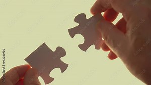 Hands connecting two puzzle pieces, symbolizing teamwork and collaboration