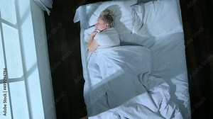 Top view of sleeping woman moves in dream changing positions in bed in room, person tossing and turning during sleep, time lapse.