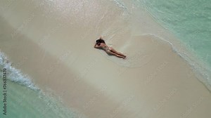 young woman tanning sunbathing woman wearing bikini at the beach on a white sand from above view from drone