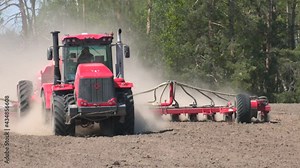 Farmer in tractor sowing crops at field with seed scattering agricultural machine. Differential agriculture. Sowing corn in dry areas. Planting corn trailed planter in the field