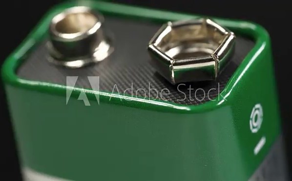 Nine-volt battery, or 9-volt battery - electric battery that supplies a nominal voltage of 9 volts. Nine-volt battery with terminals. Green 9-volt battery ready to power devices