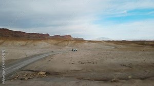 Drone flies over a car driving thru Smoky Mountain towards Alstrom Point, Lake Powell. Desert landscape with large rock formation.