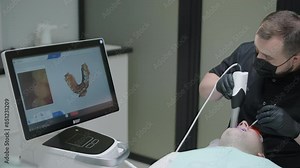 Doctor scans the patient's teeth in the clinic. The dentist holds in his hand a manual 3D scanner for the jaw and mouth. Dental health. Creates a 3D model of teeth and gums on a medical monitor.
