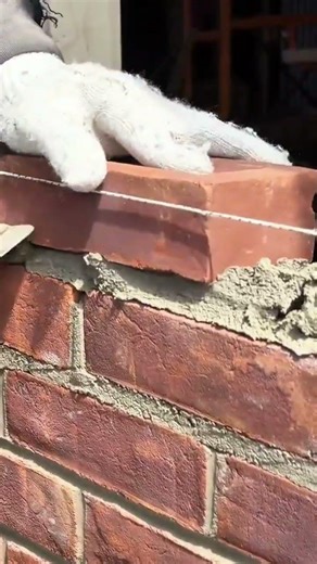 applying mortar and laying red bricks to build a sturdy wall during a construction project outdoors