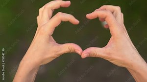 Hands throwing away a banknote and making a heart with their fingers. love or money