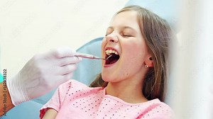 Close up of cute little girl having a dental checkup with mouth mirror, graded