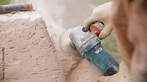 Close-up of male hands grinding a stone with an angle grinder. A man creating a stone sculpture using a grinder.