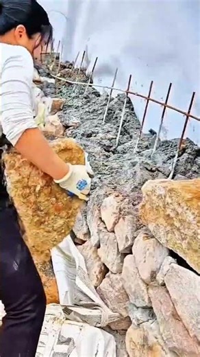 Arranging large natural stones and cement precisely to build sturdy retaining wall for construction