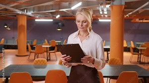 Productive Businesswoman Standing at Her Desk Working with documents, reviewing and analyzing data. Woman working with Big Data e-Commerce Analysis. Mature elegant Lady Boss in open space loft office