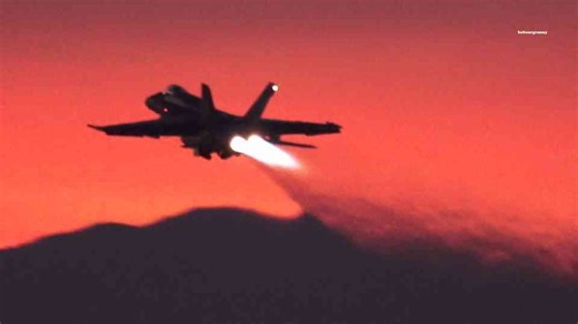 F-18 Super Hornets cut into a blood-red sky at full power
