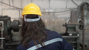 Blue collar worker is working at machine shop with welding robot arm. Factory and machinery.