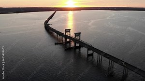 Cinematic aerial sunset view of New Youngs Bay bridge connecting Washington and Oregon United States. Drone fly above the bridge driving cars over the ocean during epic golden hours