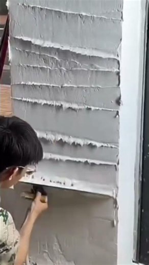 Smoothing a wet cement wall surface with long metal straight edge tool neat building finish