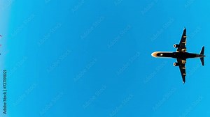 Airplane jet flying overhead against blue summer sky. Modern passenger plane flies overhead.