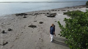 retired couple looking for small shells while on the beach in Florida