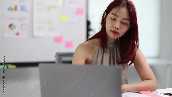 Businesswoman working on project tasks at desk in modern office, analyzing reports and taking notes office. Woman planning with sheets of paper on desk.