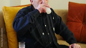 Close up of senior man drinking RAKI served with flat cylindrical glass. It is a national spirit in both Turkey and Greece. Alcoholic drink, made of grapes and raisins using the twice-distilling techn