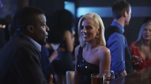 Two people talk and flirt while standing at the bar in a club