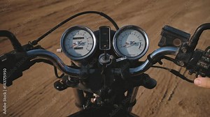 Close top view on control panel of old vintage bike, male hand turns key and starts engine, tachometer arrow shifts