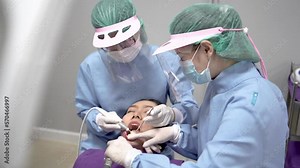 Doctor probing teeth with dental instrument using an explorer look for cavities treatment, Dental assistant assisting doctor using suction to keep patient's mouth dry during treatment procedures.