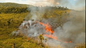 Aerial view forest fire on the slopes of hills and mountains. Forest and tropical jungle deforestation for human food farming and export. large flames from forest fire. Using fire to destroy natural