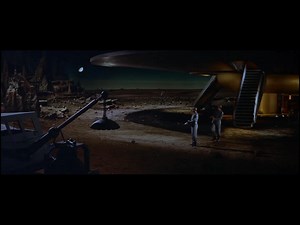 It seems to me that the ID monster can change its size, shape, and even density at will as needed. In its first attack on the ship and crew, the camera angle would suggest that it's either very large, towering over the two men, or it's a smaller, floating blob of amorphous Morbionic induced hate. I'm going with floating, as there are no footprints in the sand. In the second attack, there are very large footprints that embed deeply into the sand that also crush and bend the space metal of the asc