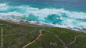 Cinematic flight over cliff edge into wild waves along Western Australia coastline.