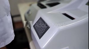 Female lab technician sets up a laboratory machine for blood analysis. Modern medical technology.