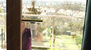 man washing the balcony window with a modern electric battery washer