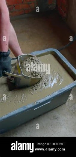 Metal texture sprayer scooping wet cement mortar from a black plastic container for wall application. Close up of plaster hopper gun being filled. Vertical video Stock Video Footage - Alamy