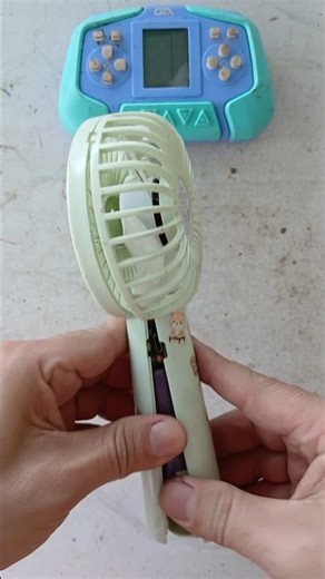 Disassembling and inspecting the inside of an old, broken mini fan for repair.