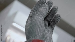 New 5-fingered metal chainmail glove with cuff for butcher's. Shot in motion. Closeup