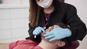 Female dentist wearing protective gloves and a mask examining a...