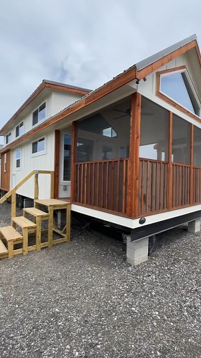 Could you live in this 399-sqft "Barn Owl" park model tiny house with a ground-floor bedroom? At the entrance of the tiny home, you have a screened-in porch, perfect for having your morning cup of coffee. Inside, there's a beautiful U-shaped kitchen with full-size appliances, a living room, a laundry area with room for side-by-side washer and dryer, a full bathroom with a tile shower, a ground-floor bedroom with built-in storage, and a set of storage stairs taking you up to the bonus loft space!