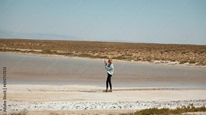 Female traveler capturing vast expanse of Salty Lake Tuz in Turkey with her mobile phone. Panoramic view shows mesmerizing white crystallized surface of lake with salt.