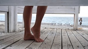 Woman in the changing, dressing room on the beach, at sunset on the seashore. The girl changes clothes, throwing up a swimsuit, then leaves the locker room in a pink dress. Close up, slow motion