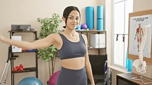 Young woman flexing muscles confidently in physical therapy rehab clinic, portraying strength and recovery.