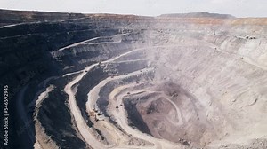 Aerial view of industrial opencast mining quarry with lots of machinery at work extracting mining ore for the metal industry. Coal mining industrial crater, Open pit iron ore mining, moving camera