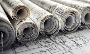 The image features rolled architectural blueprints placed on a flat surface, showcasing detailed plans for construction or design projects.