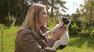 A beautiful young woman hugs her adorable puppy in the park. A little girl plays with her dog, a wonderful breed best friend. She teases, caresses and scratches a super happy dog.