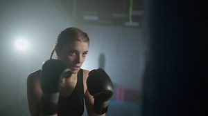 Woman power, female fighter beats a punching bag, trains his punches, training day in the boxing gym, the female strikes fast, cinematic lighting.
