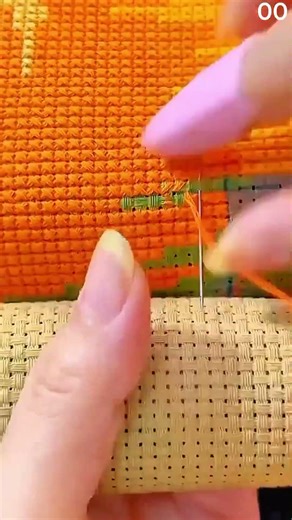 Orange thread stitched in cross pattern on fabric grid